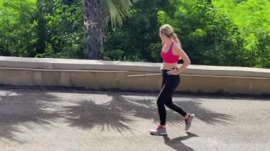 Bir kadın, yemyeşil ve çarpıcı kıyı manzaralarıyla çevrili güzel, dolambaçlı bir yolda koşuyor.