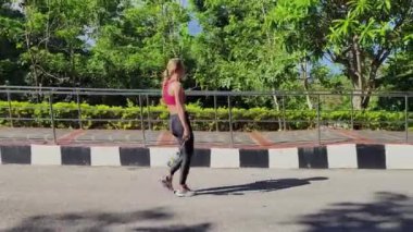 Bir kadın, yemyeşil ve çarpıcı kıyı manzaralarıyla çevrili güzel, dolambaçlı bir yolda koşuyor.