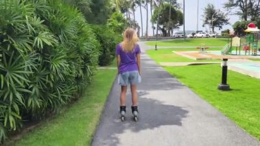 Bir kadın, güzel bir park ortamında uzanan manzaralı bir yolda paten kaymaktan zevk alıyor..