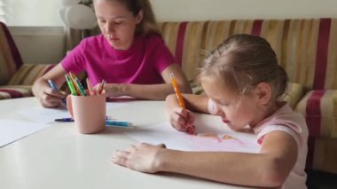 Bir anne ve kızı evde birlikte boyama faaliyetlerinde bulunuyorlar.