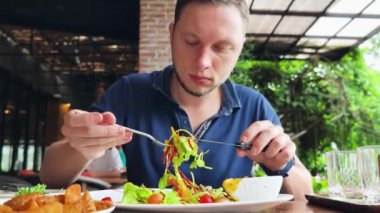 Bir adam modern bir kafe ortamında keyifli bir yemek ve içecekten zevk alıyor.