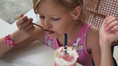 Küçük bir kız mutlu bir şekilde dondurmanın tadını çıkarıyor.