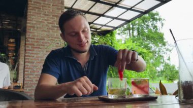 Bir adam modern bir kafe ortamında keyifli bir yemek ve içecekten zevk alıyor.