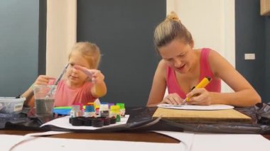 Bir anne ve küçük kızı, yaratıcılığı teşvik eden renkli bir resim faaliyetinde bulunuyorlar.
