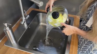 Bir kadın güzel tasarlanmış modern mutfakta ustalıkla lezzetli bir patates hazırlıyor.