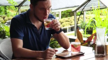 Bir adam modern bir kafe ortamında keyifli bir yemek ve içecekten zevk alıyor.