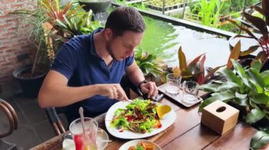 Bir adam modern bir kafe ortamında keyifli bir yemek ve içecekten zevk alıyor.