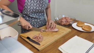 Genç bir kadın, modern mutfakta çiğ eti hamburgerlere hazırlıyor. 