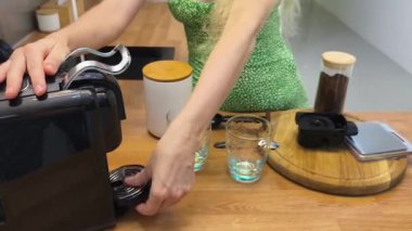 Genç bir kadın güzel tasarlanmış modern mutfakta taze kahve hazırlıyor.