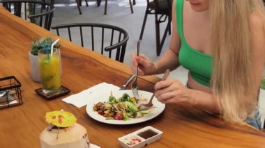 Bir kadın, modern bir kafe ortamında hoş bir yemeğin tadını çıkarıyor.