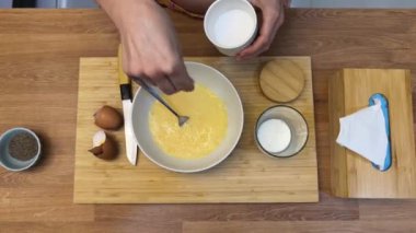 Bir kadın güzel tasarlanmış modern mutfakta ustalıkla lezzetli bir yumurta hazırlıyor.