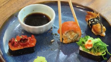 Sıcak bir yemek masasında oturmuş lezzetli suşiden zevk alan genç bir kadın. 