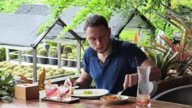 Bir adam modern bir kafe ortamında keyifli bir yemek ve içecekten zevk alıyor.
