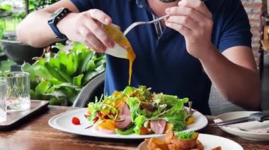 Bir adam modern bir kafe ortamında keyifli bir yemek ve içecekten zevk alıyor.