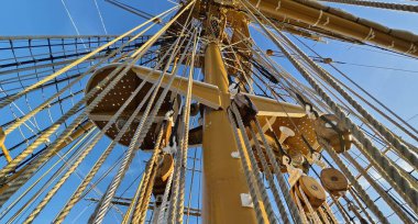 Eski bir geminin direkleri boyunca uzanan uzun ipler.