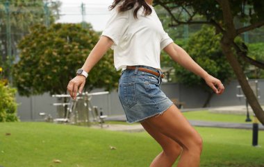 Güzel genç bir kadın ustalıkla kaykayla parktan geçiyor.