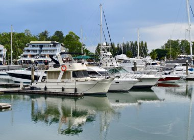 Huzurlu ve huzurlu bir yat limanı sahnesi. Çeşitli tekneler ve uzun deniz fenerleri var.