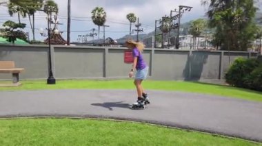 Bir kadın, güzel bir park ortamında uzanan manzaralı bir yolda paten kaymaktan zevk alıyor..