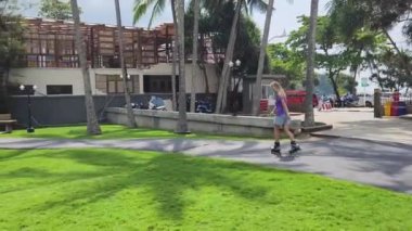 Bir kadın, güzel bir park ortamında uzanan manzaralı bir yolda paten kaymaktan zevk alıyor..