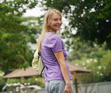 Bir kadın, güzel bir park ortamında uzanan manzaralı bir yolda paten kaymaktan zevk alıyor..