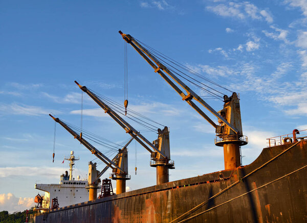 A substantial large ship equipped with cranes mounted on its side