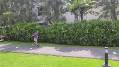 Bir kadın, güzel bir park ortamında uzanan manzaralı bir yolda paten kaymaktan zevk alıyor..