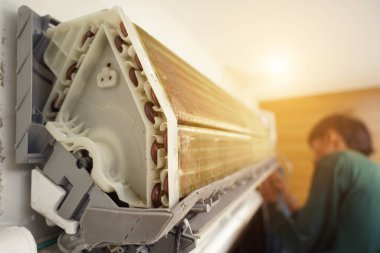 İşçi düzgün çalışması için klimayı temizler ve onarır..