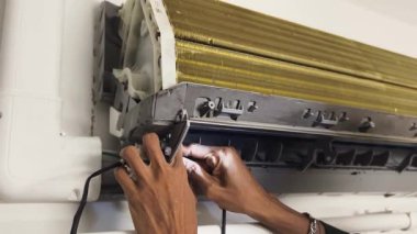 Bir teknisyen duvara monte edilmiş klimayı tamir eder ve havalandırma sistemini tamir eder.. 