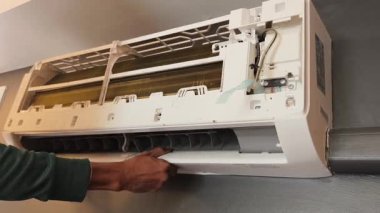 Bir teknisyen duvara monte edilmiş klimayı tamir eder ve havalandırma sistemini tamir eder.. 