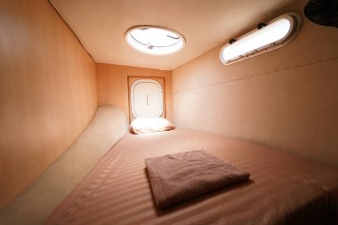 Yolculuk teknesinde rahat bir yatak ve üzerinde doğal ışık olan bir pencere..