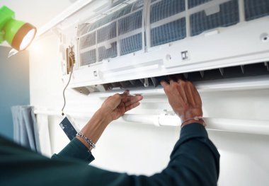 İşçi düzgün çalışması için klimayı temizler ve onarır..