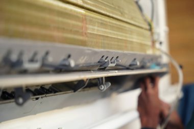 İşçi düzgün çalışması için klimayı temizler ve onarır..