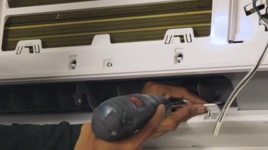 Bir teknisyen duvara monte edilmiş klimayı tamir eder ve havalandırma sistemini tamir eder.. 