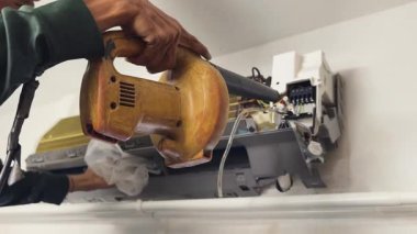 Bir teknisyen duvara monte edilmiş klimayı tamir eder ve havalandırma sistemini tamir eder.. 