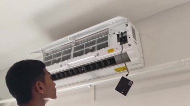 Bir teknisyen duvara monte edilmiş klimayı tamir eder ve havalandırma sistemini tamir eder.. 