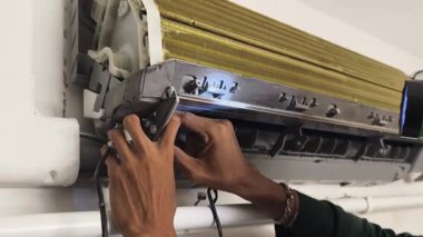 Bir teknisyen duvara monte edilmiş klimayı tamir eder ve havalandırma sistemini tamir eder.. 