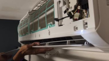 Bir teknisyen duvara monte edilmiş klimayı tamir eder ve havalandırma sistemini tamir eder.. 