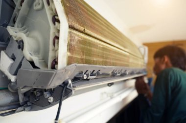 İşçi düzgün çalışması için klimayı temizler ve onarır..