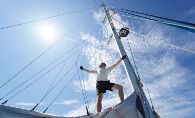Erkek kaptan gururla bir yelkenlide durup anın tadını çıkarıyor..