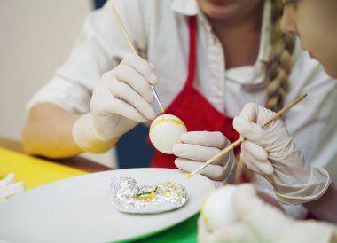 Anne ve kızı geleneksel Ukrayna kostümleriyle Paskalya için yumurta boyuyor..