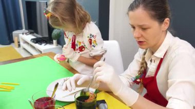 Anne ve kızı geleneksel Ukrayna kostümleriyle Paskalya için yumurta boyuyor..