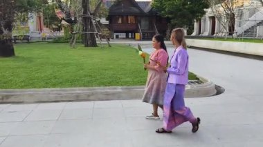 İki Taylandlı kadın Budist tapınağının huzurlu ortamında vakit geçirir..
