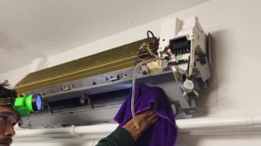 Bir teknisyen duvara monte edilmiş klimayı tamir eder ve havalandırma sistemini tamir eder.. 