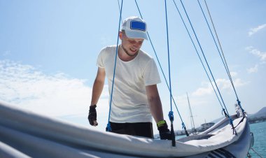 Yelkenli güvertesinde yelkenlileri açan erkek kaptan fermuarı çekiyor..