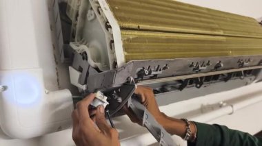 Bir teknisyen duvara monte edilmiş klimayı tamir eder ve havalandırma sistemini tamir eder.. 