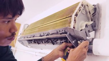 Bir teknisyen duvara monte edilmiş klimayı tamir eder ve havalandırma sistemini tamir eder.. 