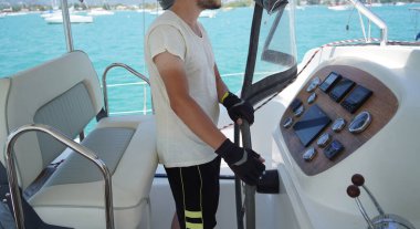 Siyah eldivenli genç erkek kaptan, dümen dümeni..