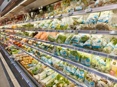 Bir market koridorunda geniş bir meyve ve sebze seçeneği sunulmaktadır..