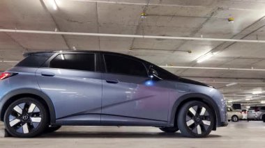 Modern bir elektrikli araç, çağdaş bir otoparkın içine park ediyor..
