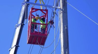  Asansördeki iki yetenekli işçi, uzun direğin elektrik bakımında güvenliği sağlıyorlar..